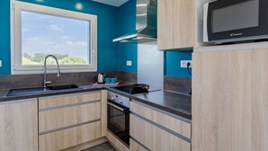 Eine moderne Küche mit Türkiswänden, einer Edelstahl-Spüle, einer Mikrowelle und Holzschränken.