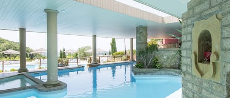 An indoor swimming pool with a stone wall and a wooden ceiling.