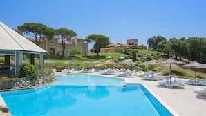 A swimming pool with lounge chairs and umbrellas, surrounded by buildings and trees. - Il Felciaione by Interhome (Riparbella)