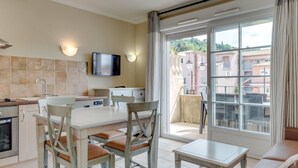 Une cuisine moderne avec un coin repas, un téléviseur fixé au-dessus du comptoir et une vue sur la ville grâce à de grandes fenêtres.