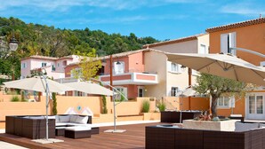 Une cour avec des espaces de détente en plein air, une terrasse en bois et des bâtiments dotés de balcons.