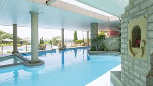 Une piscine intérieure avec un mur en pierre et un plafond en bois.