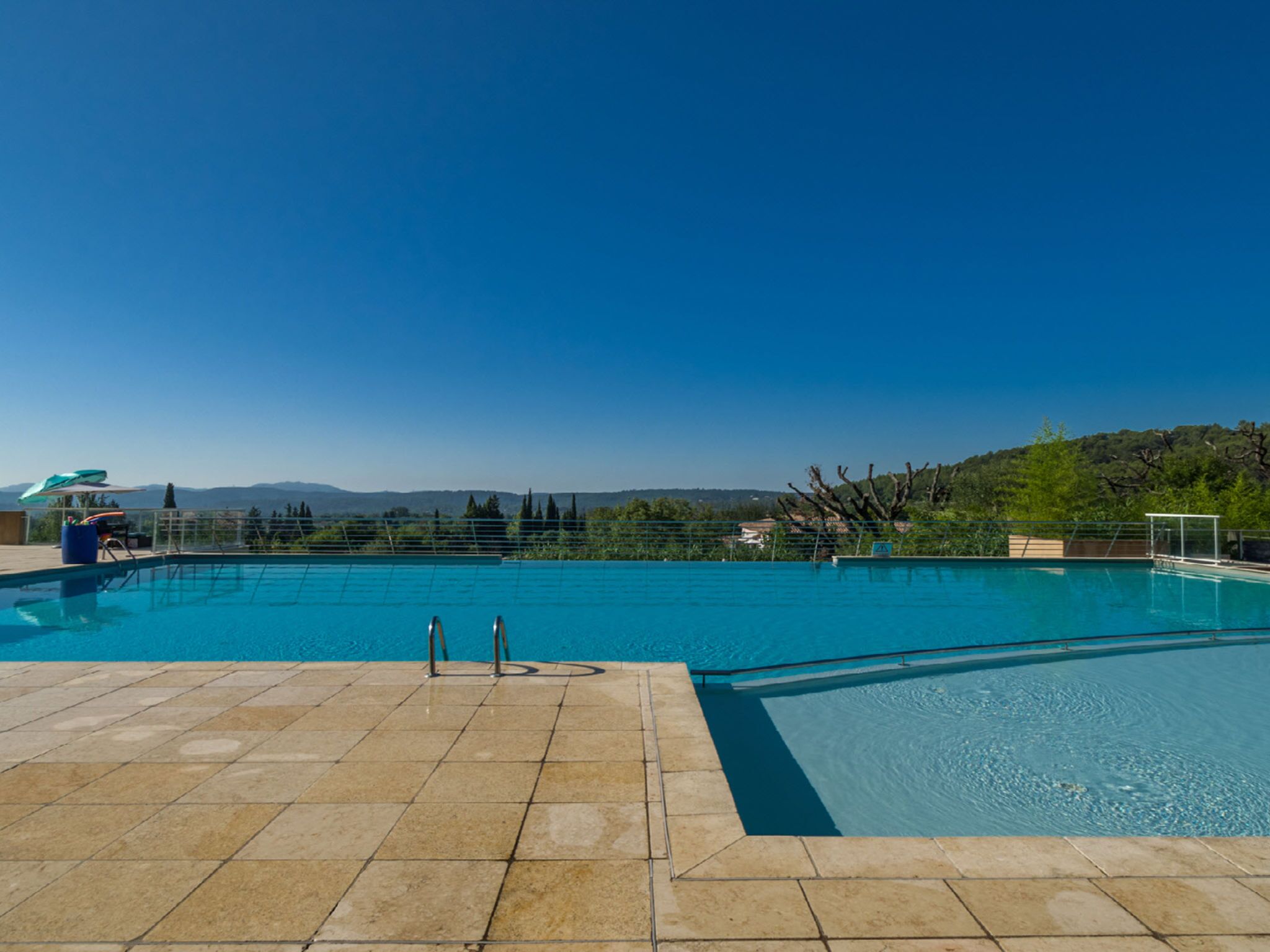 A swimming pool with clear blue water, surrounded by a tiled deck.