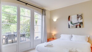 Camera d'albergo con un letto grande, un comodino con una lampada, un quadro appeso e vista all'esterno tramite una porta scorrevole.