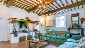 A rustic kitchen with wooden beams, a green sofa, and a coffee table. - Fattoria di Scaletta by Interhome (San Miniato)