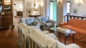 Ein gemütliches Wohnzimmer mit einer Couch, einem Sessel und einem Tisch mit einer Dekotasse.