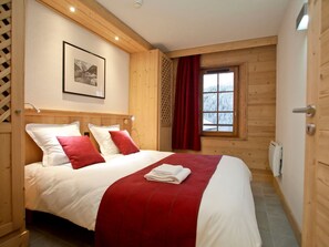 Cozy bedroom with a large bed, wooden paneling, and a framed photograph.