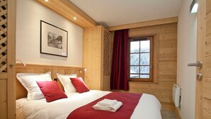 Une chambre à coucher aux murs lambrissés, avec un lit, un tableau encadré et une fenêtre avec des rideaux.