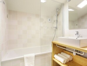 Bathroom features a glass-enclosed shower, wall-mounted showerhead, and handheld shower attachment.