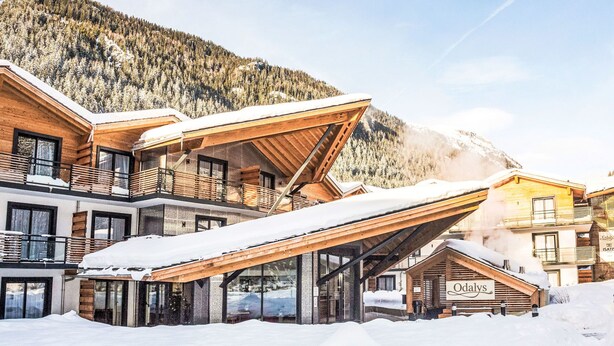 A modern ski resort building with multiple levels, large glass windows, and wooden balconies.