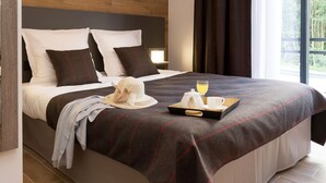 A hotel room with a large bed, a wooden headboard, and a window with curtains.
