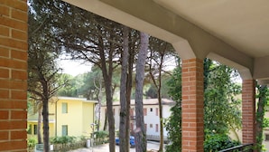A balcony with a brick railing overlooking a courtyard with trees and buildings. - Casa Sandra by Interhome (Rosolina Mare)