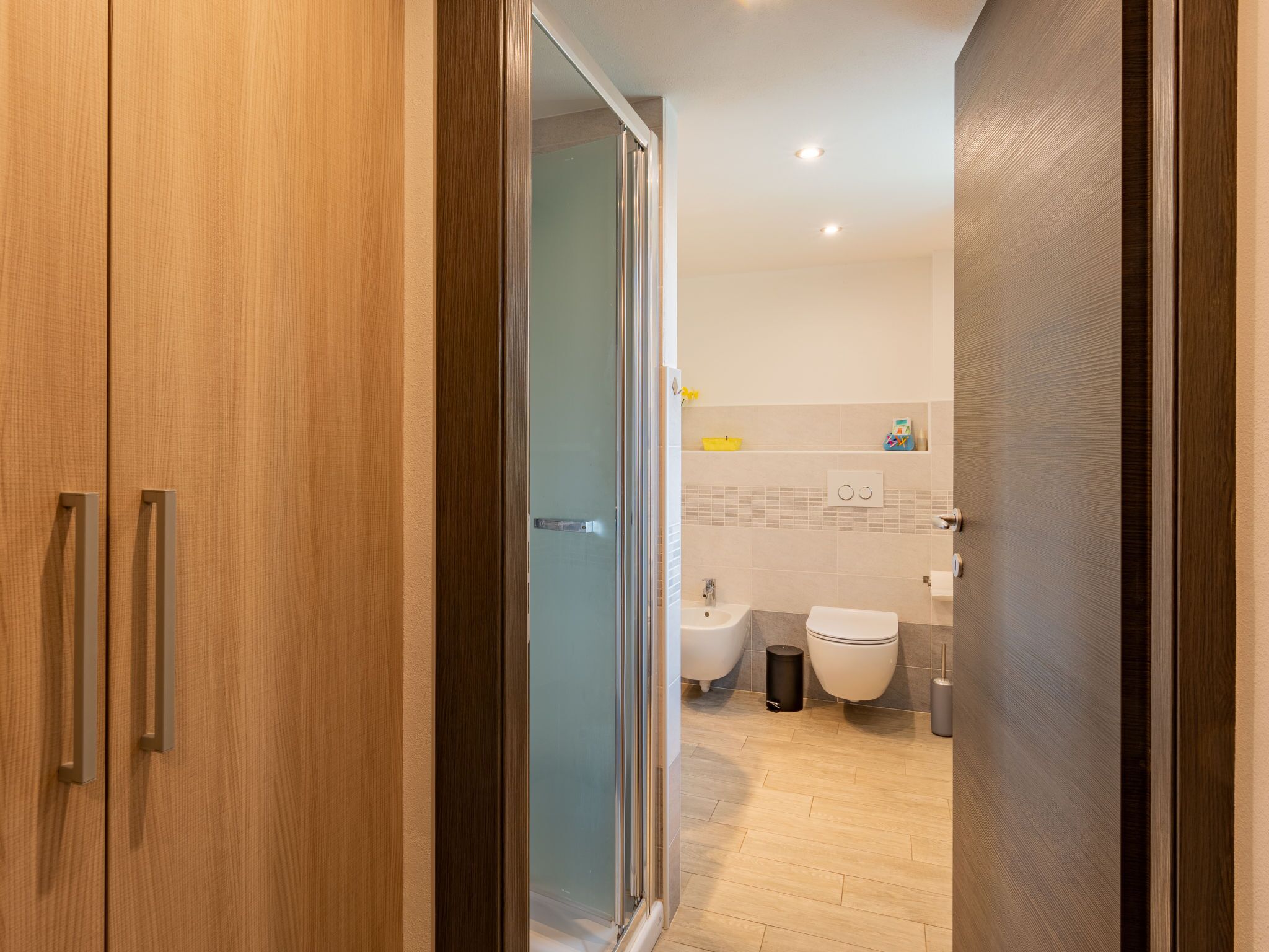 A modern bathroom with a glass shower enclosure, a toilet, and a bidet.