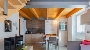Un espace de vie compact comprenant une cuisine, un coin repas et un espace détente avec un téléviseur et un canapé.