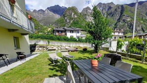 Eine Terrasse mit Tisch und Stühlen, einem Blumentopf und Blick auf Berge im Hintergrund.