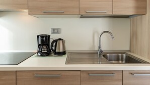 Eine moderne Küche mit Holzausstattung, einer Edelstahlspüle, einer Kaffeemaschine und einem Wasserkocher.