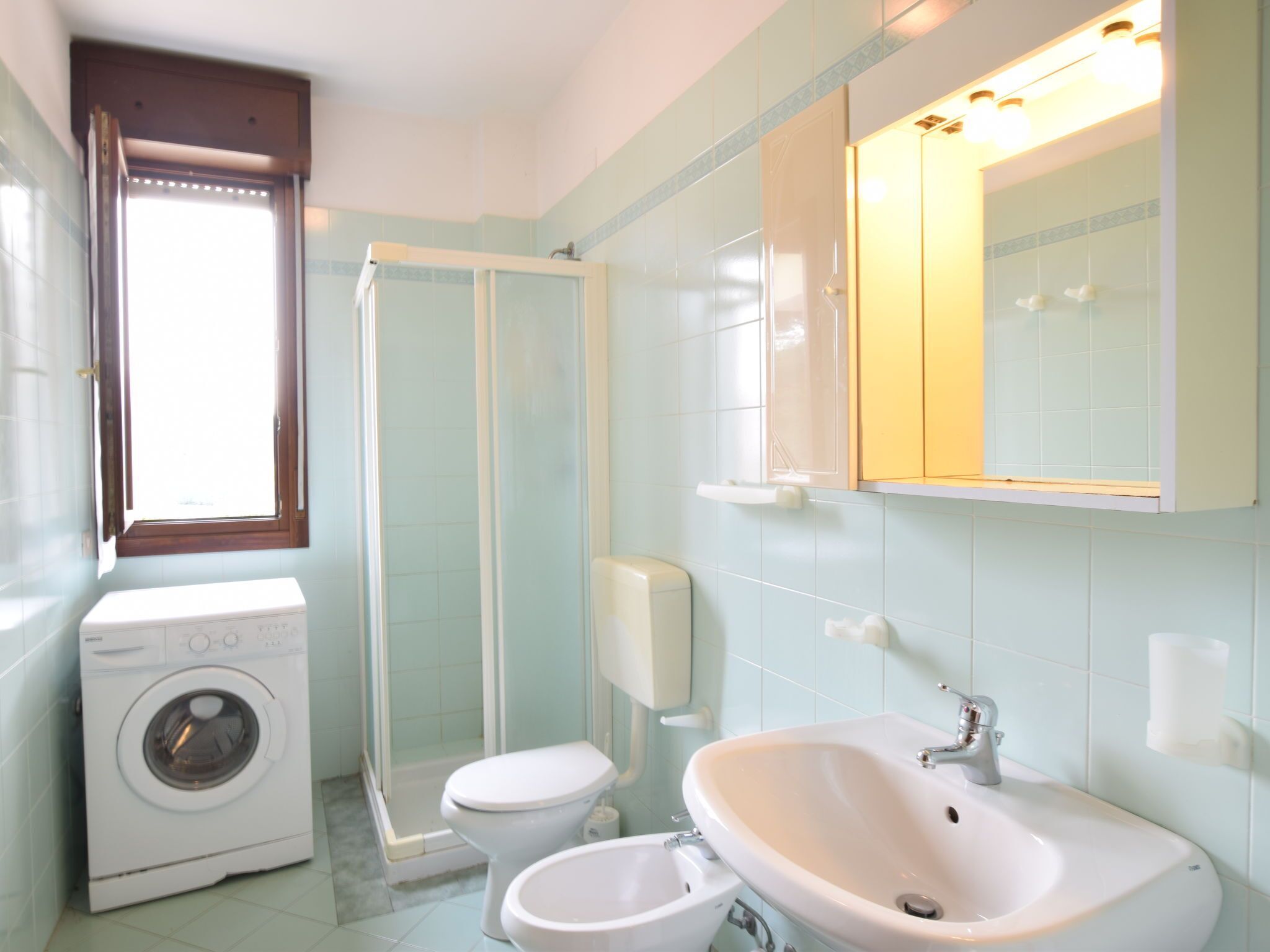 Ein Badezimmer mit Waschmaschine, Toilette, Dusche und Waschbecken.