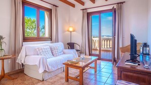 A cozy room with a bed, a table, and a TV. There are curtains, a lamp, and a view of the outside. - Finca Can Corritx by Interhome (Muro)