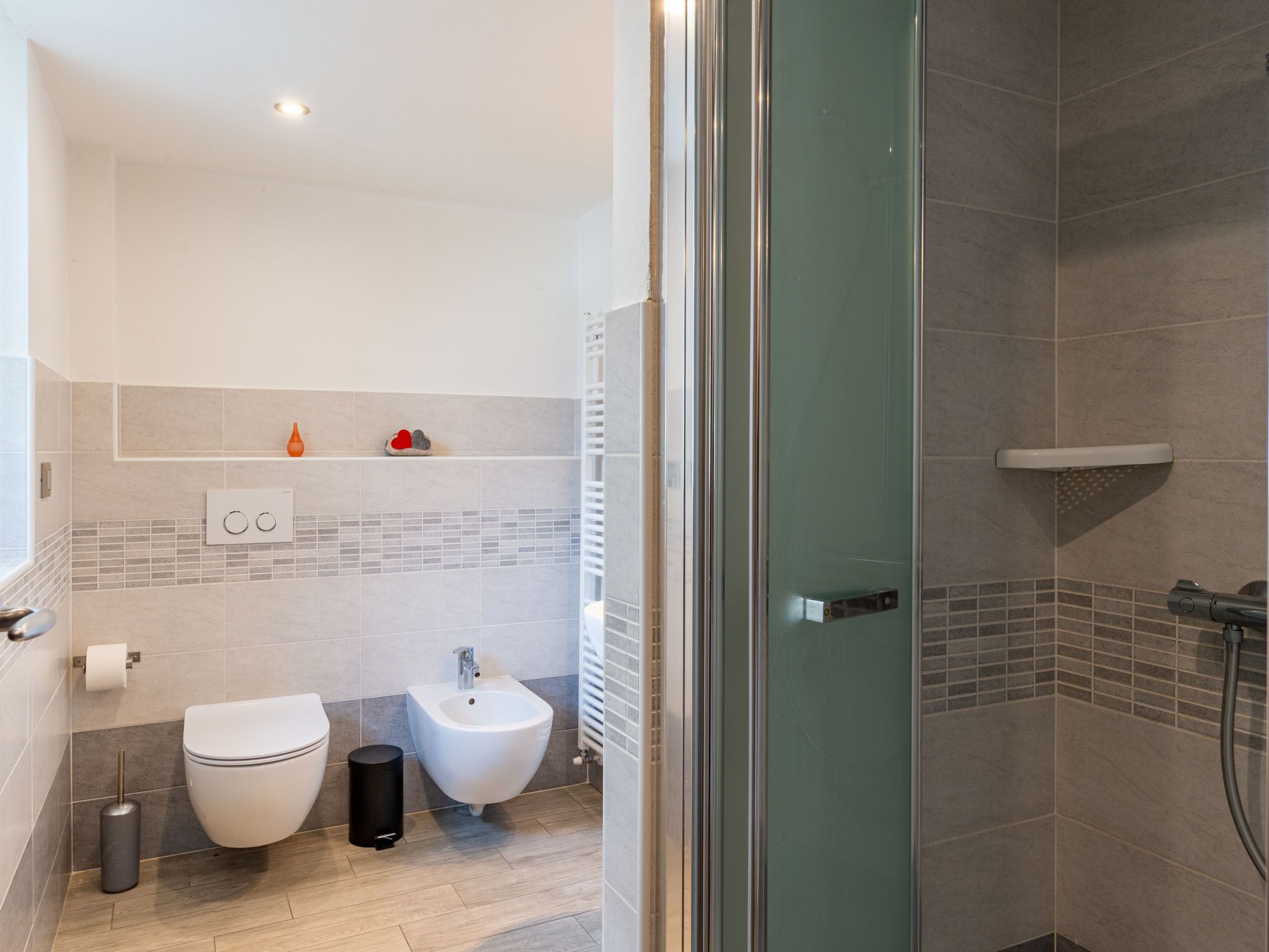A modern bathroom with a toilet, bidet, and shower.