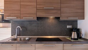 A modern kitchen with wooden cabinets, a stainless steel sink, a black countertop, and a coffee maker. - Apartment Marco by Interhome (Lago di Mezzola)