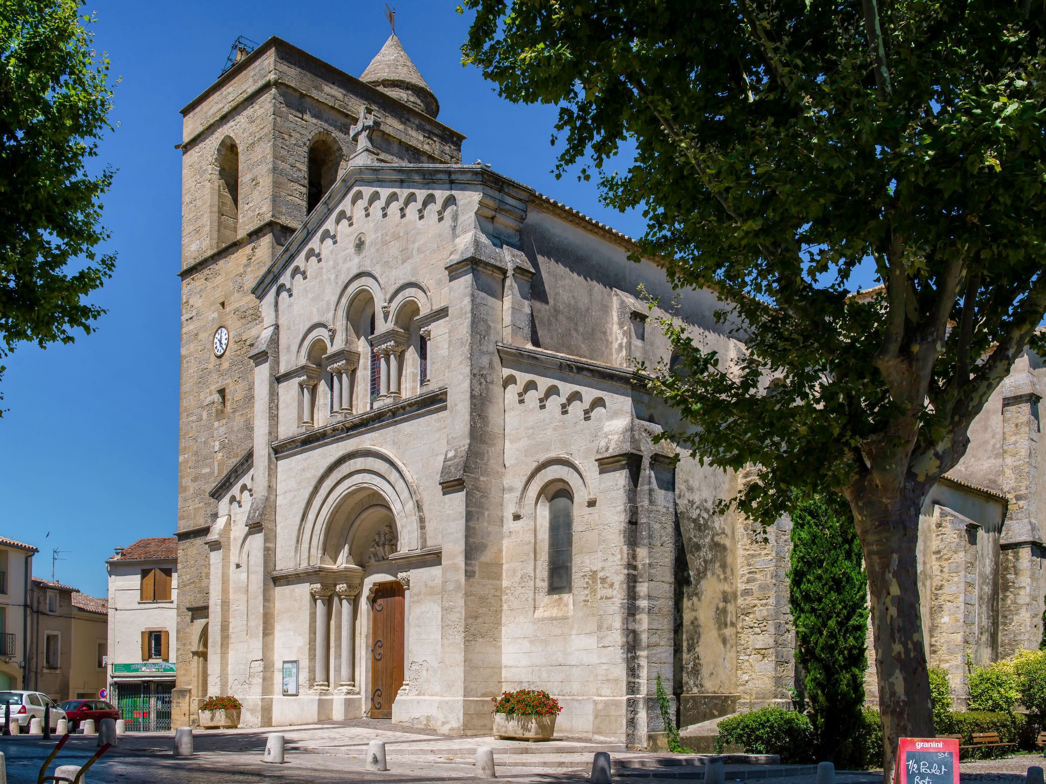 Una iglesia de piedra histórica con un campanario, ventanas de arco y una puerta de madera.