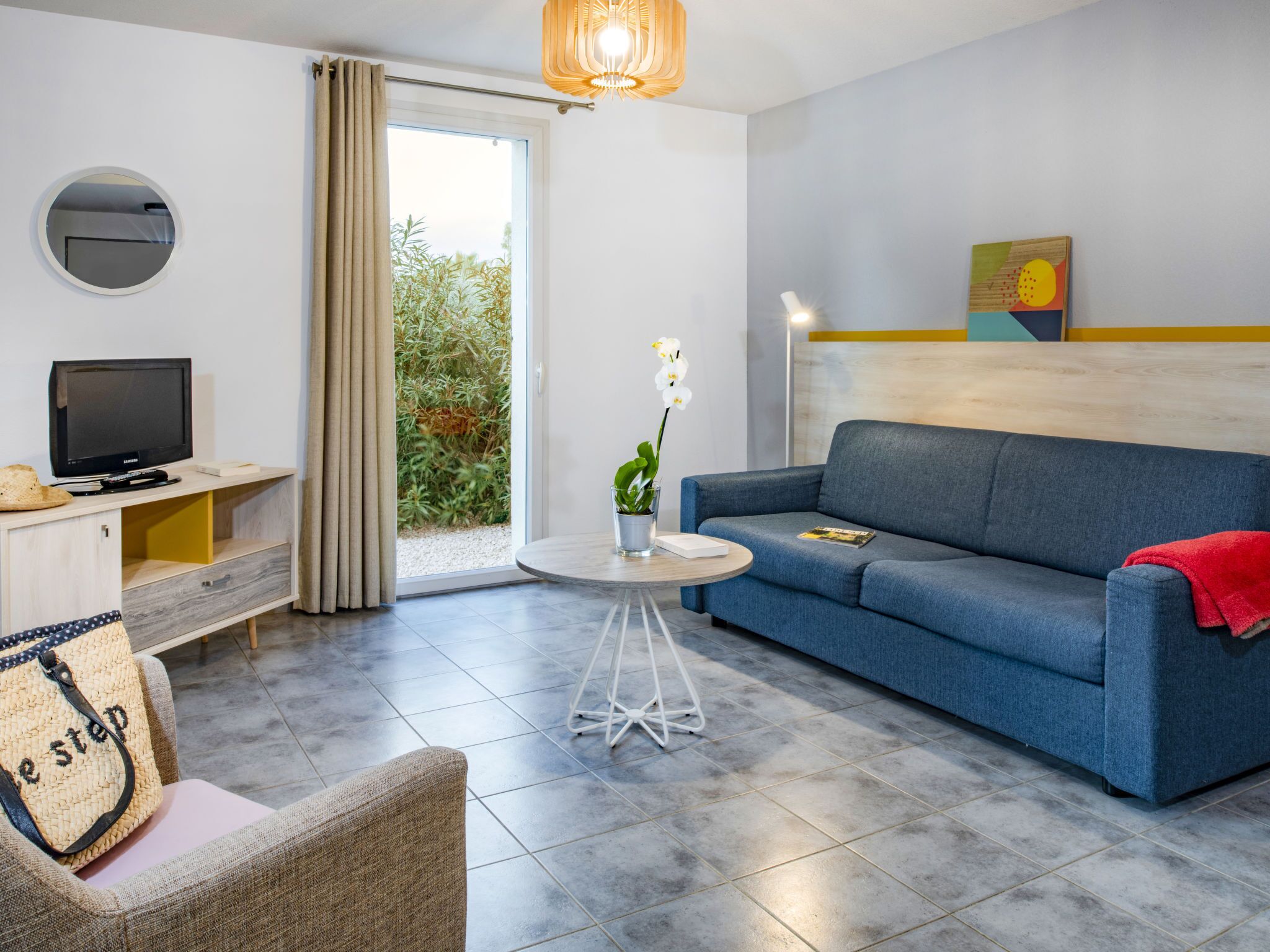 Un salon moderne avec un canapé, un téléviseur et une petite table sur laquelle est posée une plante.