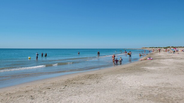 A beach with people walking along the shore, some in the water, and beachgoers relaxing on the sand. - Domaine du Golf by Interhome (Montpellier)