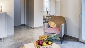 A modern interior with a dining area, a chair with a hat, and a fruit basket. - Domaine du Golf by Interhome (Montpellier)