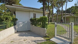A single-story building with a white exterior, a small porch, and a gated entrance. - Missana by Interhome (Lignano Riviera)