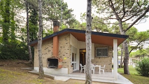 A small brick house with a chimney, a patio with chairs, and a stone pathway. - Villaggio Laura by Interhome (Lignano Riviera)