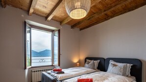 Een slaapkamer met twee bedden, een groot raam met uitzicht op bergen en een houten plafond.