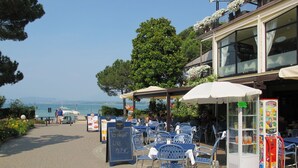 An outdoor café with tables and chairs, a chalkboard sign, and a vending machine.