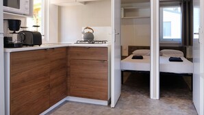 A compact room with a kitchenette, a bed, and a window.