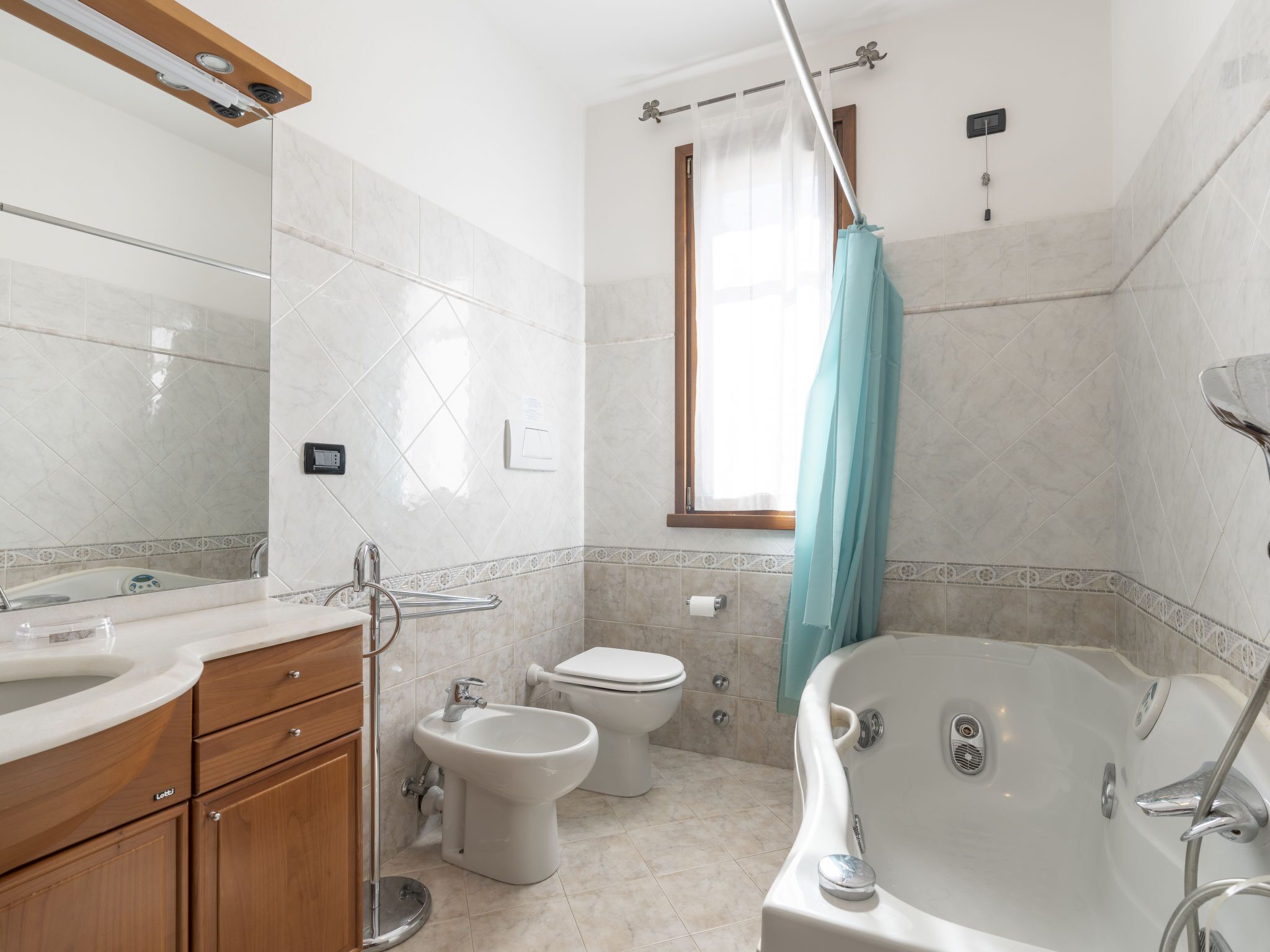 A modern bathroom with a bathtub, bidet, toilet, and vanity.