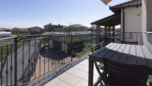Un balcón con vistas a un jardín y edificios a lo lejos.