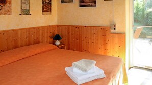 A room with a large bed, wooden paneling on the walls, and a window with a view of greenery.