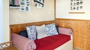 A cozy room with a wooden headboard sofa, a red blanket, and a small wooden table with books.