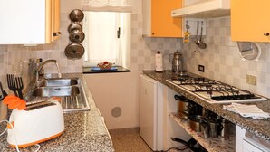 A compact kitchen with a gas stove, a sink, and a small refrigerator.