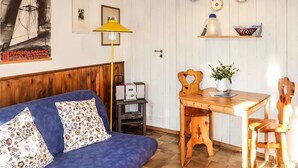 Une pièce chaleureuse avec un canapé bleu, une table à manger en bois et une lampe jaune.
