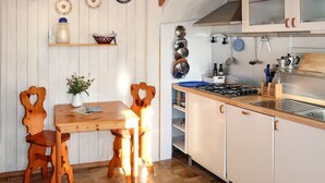 Une cuisine avec des meubles en bois, une cuisinière à gaz et divers ustensiles de cuisine.