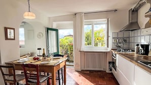 Une cuisine avec une table à manger, des chaises et une vue sur le jardin.