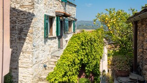 Un bâtiment en pierre avec des volets verts, un escalier et une vue sur la campagne.