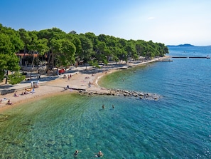 A beach with clear water, trees, and people. - Vacation home Tina by Interhome (Biograd na Moru)