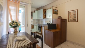 Une cuisine compacte comprenant une table à manger, des chaises, un réfrigérateur et un téléviseur.
