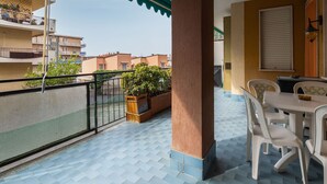 Un balcon doté d’un sol carrelé, d’une table avec des chaises et offrant une vue sur les bâtiments voisins.