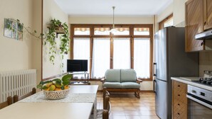 A modern kitchen with a dining area, a TV, and a sofa.