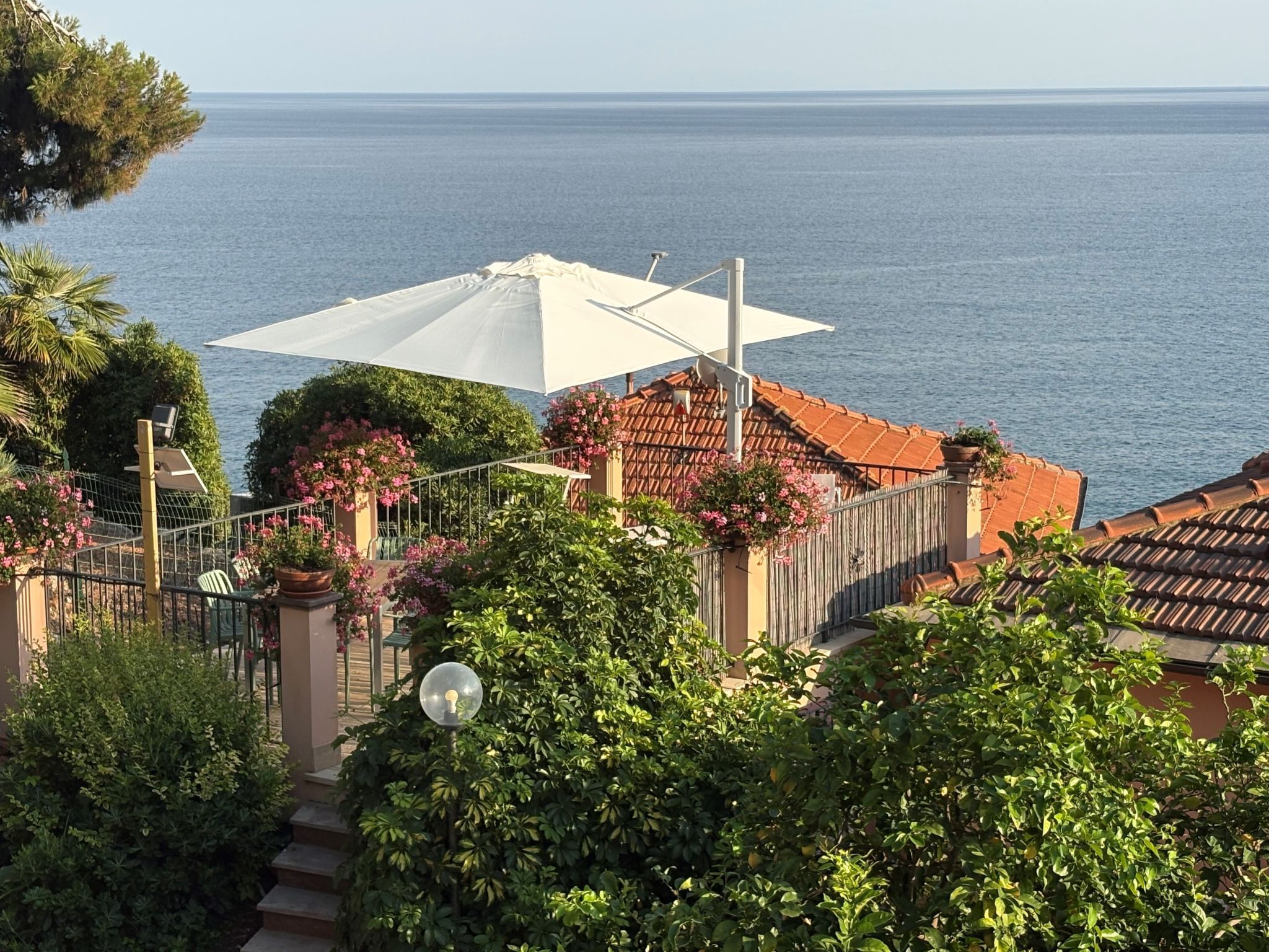 Una propiedad costera con terraza, plantas en macetas y vista al mar.