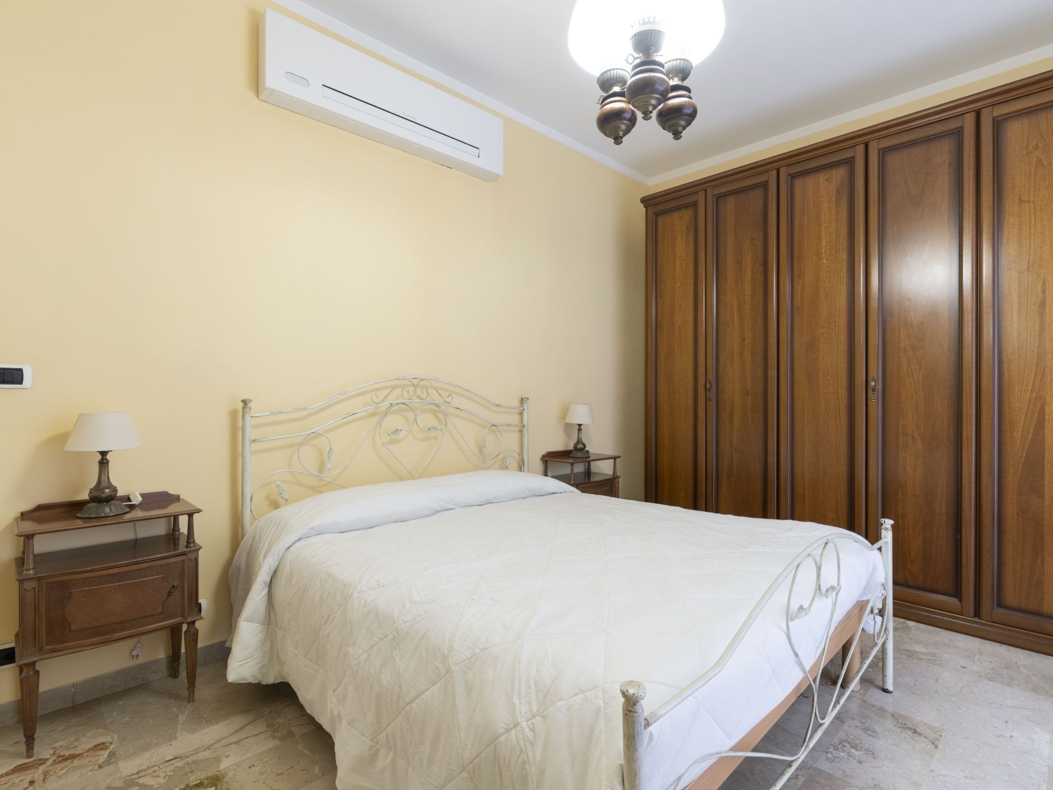 Una camera da letto con un letto, un'armadio in legno, comodini e un condizionatore d'aria.