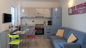 A compact kitchen with a dining area, a sofa, and a flat-screen TV. - Toni (TZR240) by Interhome (Terzorio)
