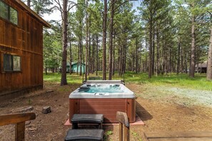 A wooden cabin with a hot tub in a forested area. - Charming Modern A-frame Chalet with Hot Tub--8 min walk to Country Club (Angel Fire)